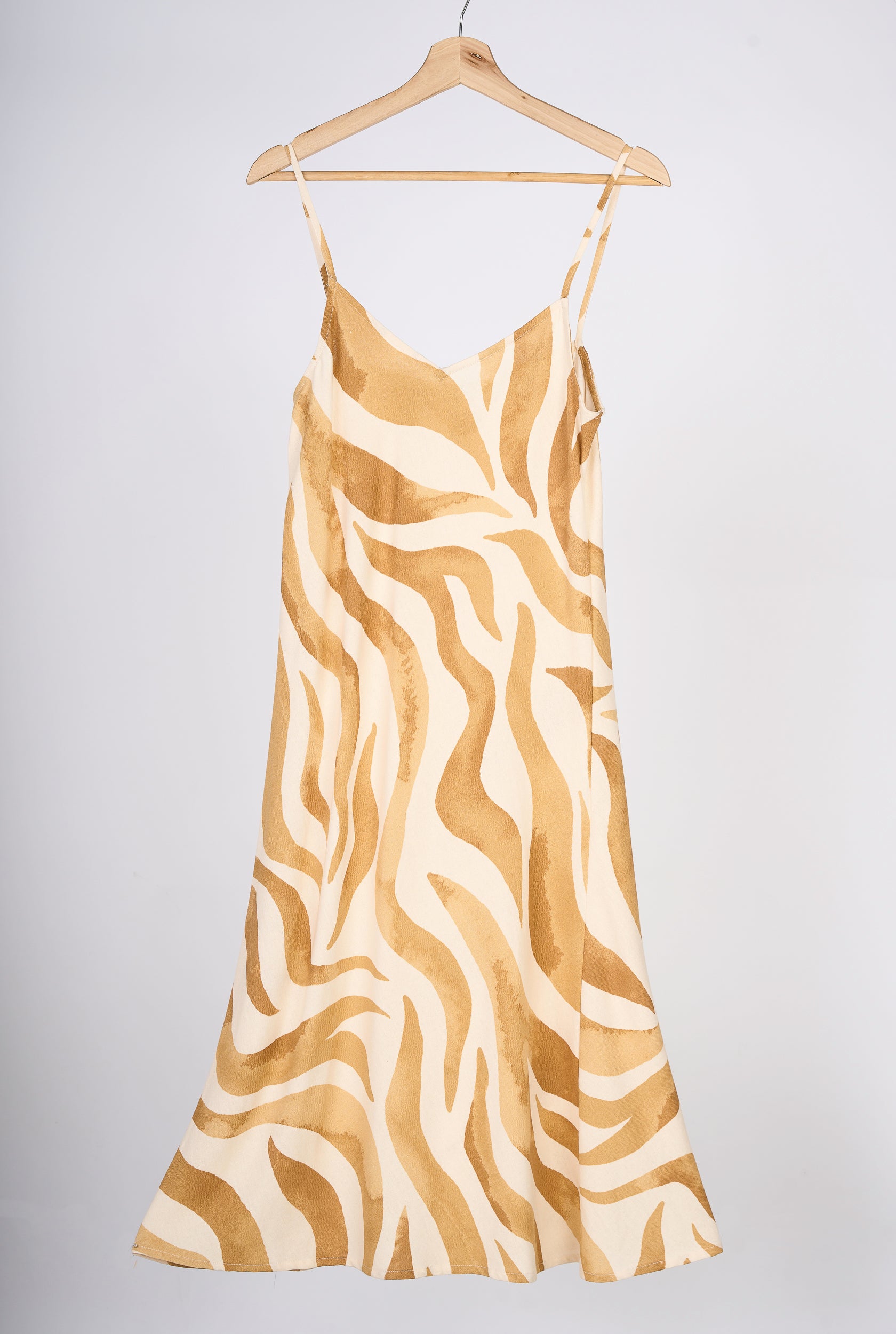 Slipdress de flores color mostaza, en colgador marrón.