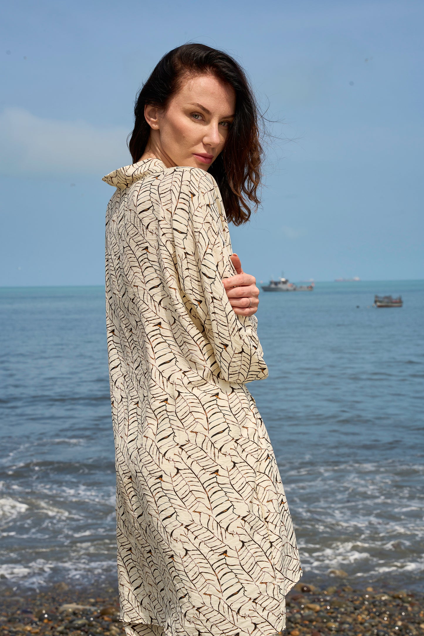 Mujer con bata a rayas junto a orilla del mar