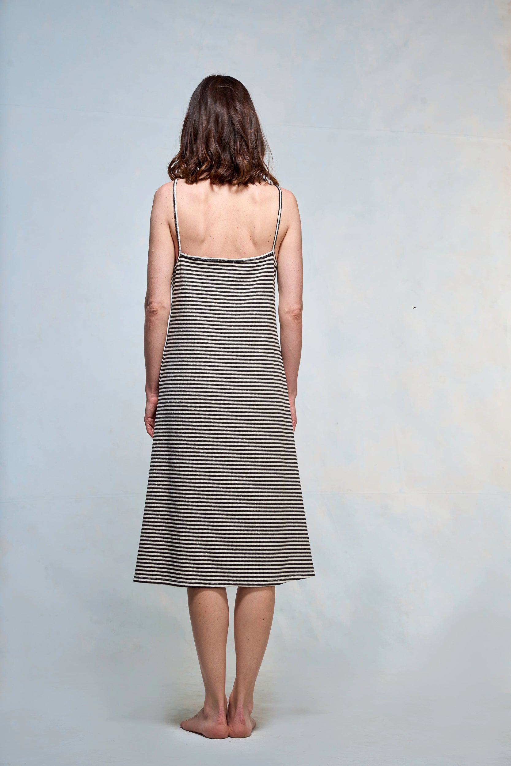 Mujer de espaldas, vestida con slipdress a rayas blancas y negras.