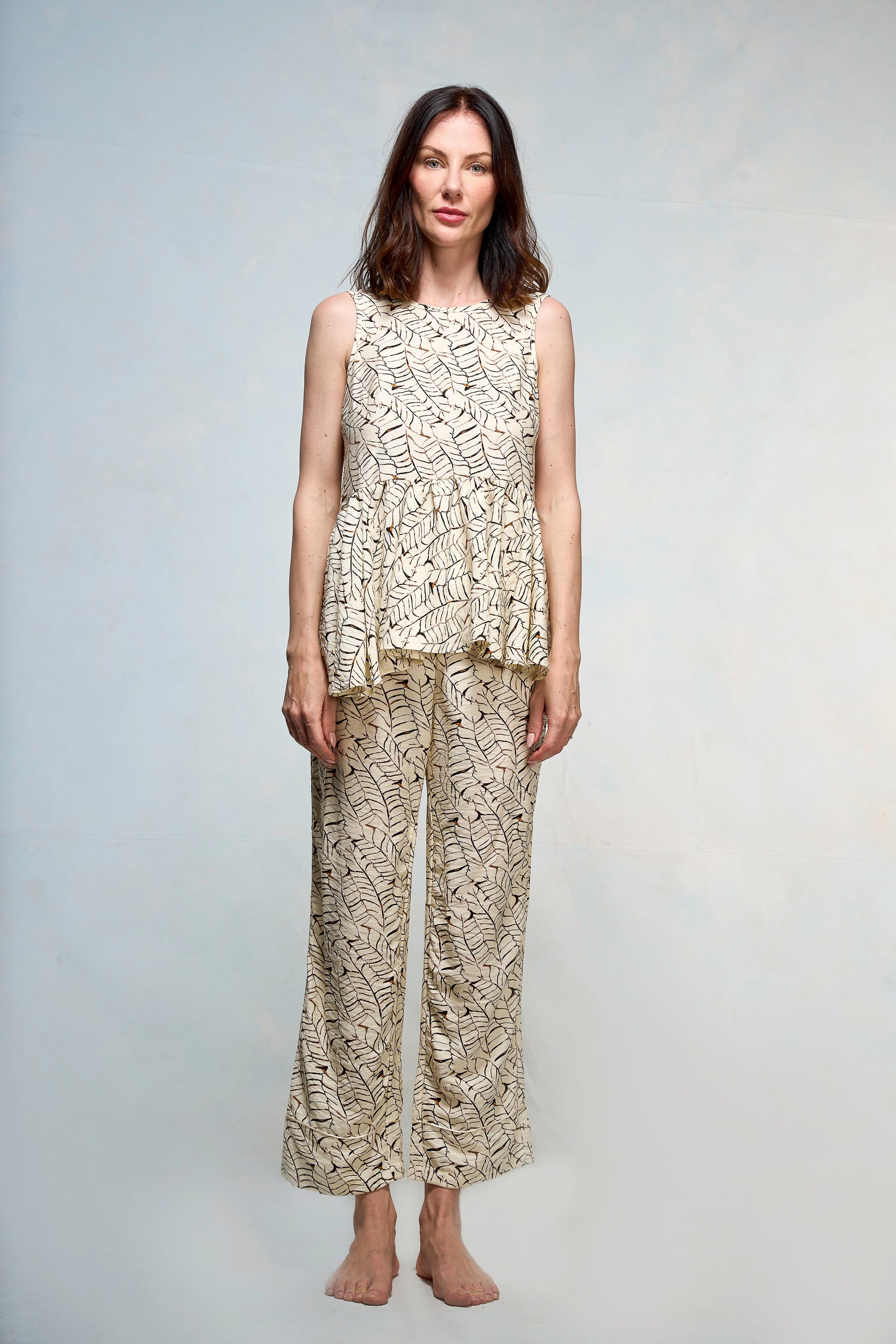 Mujer vestida con blusa y pantalón beige con print de hojas