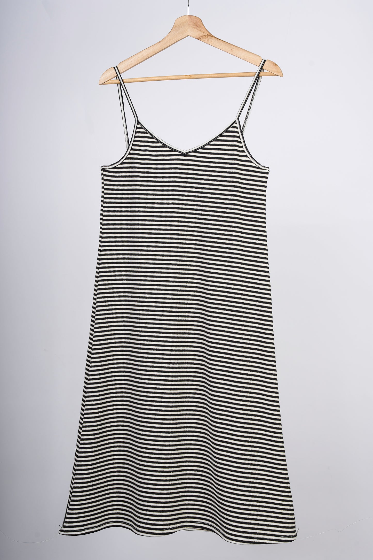 Slipdress a rayas blancas y negras, en colgador marrón.