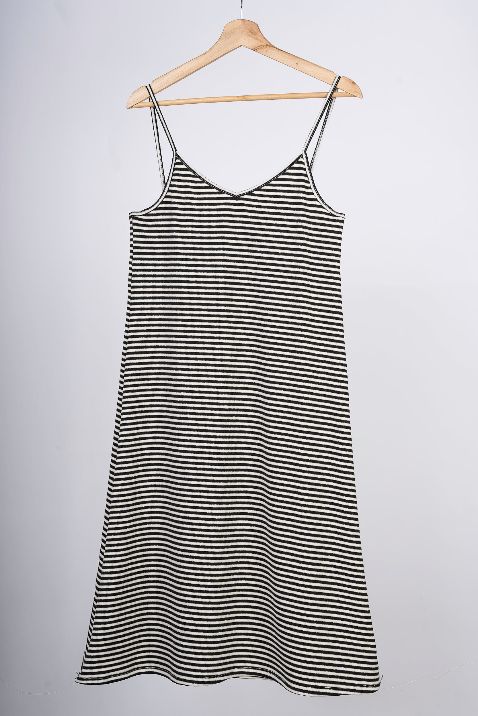 Slipdress a rayas blancas y negras, en colgador marrón.