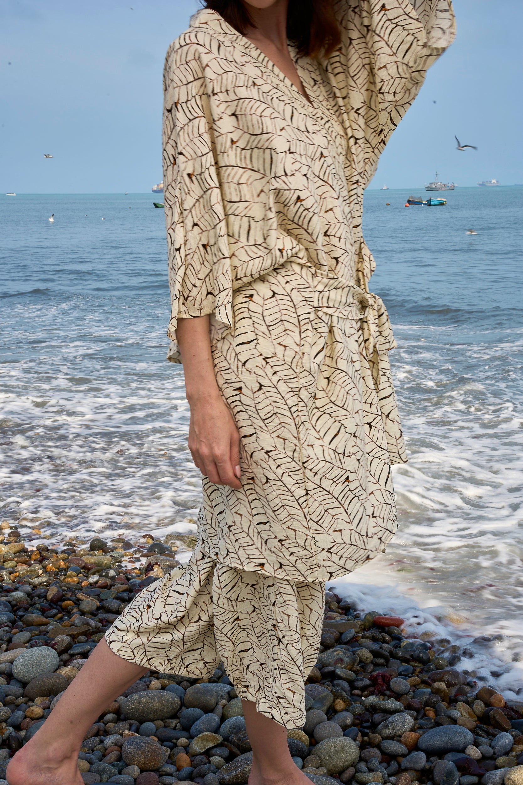 Mujer con bata a rayas junto a orilla del mar