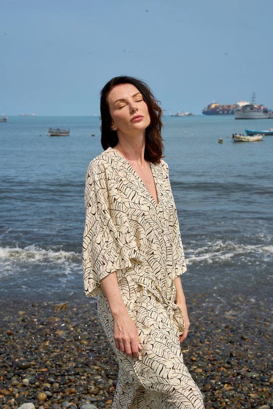 Mujer con bata a rayas junto a orilla del mar