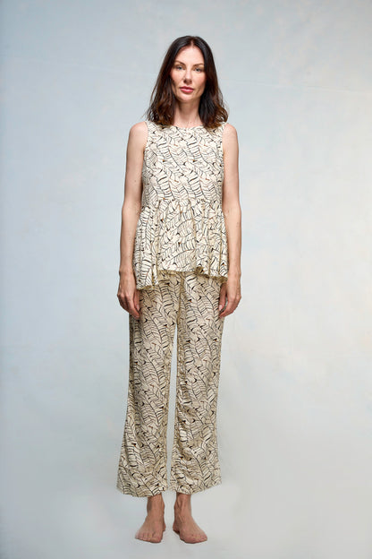 Mujer vestida con blusa y pantalón beige con print de hojas