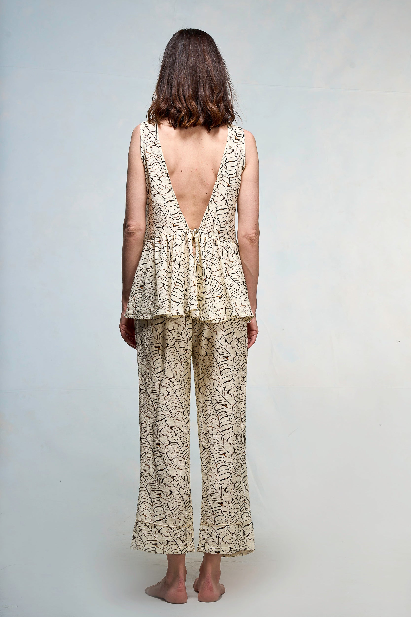 Mujer vestida con blusa y pantalón beige con print de hojas